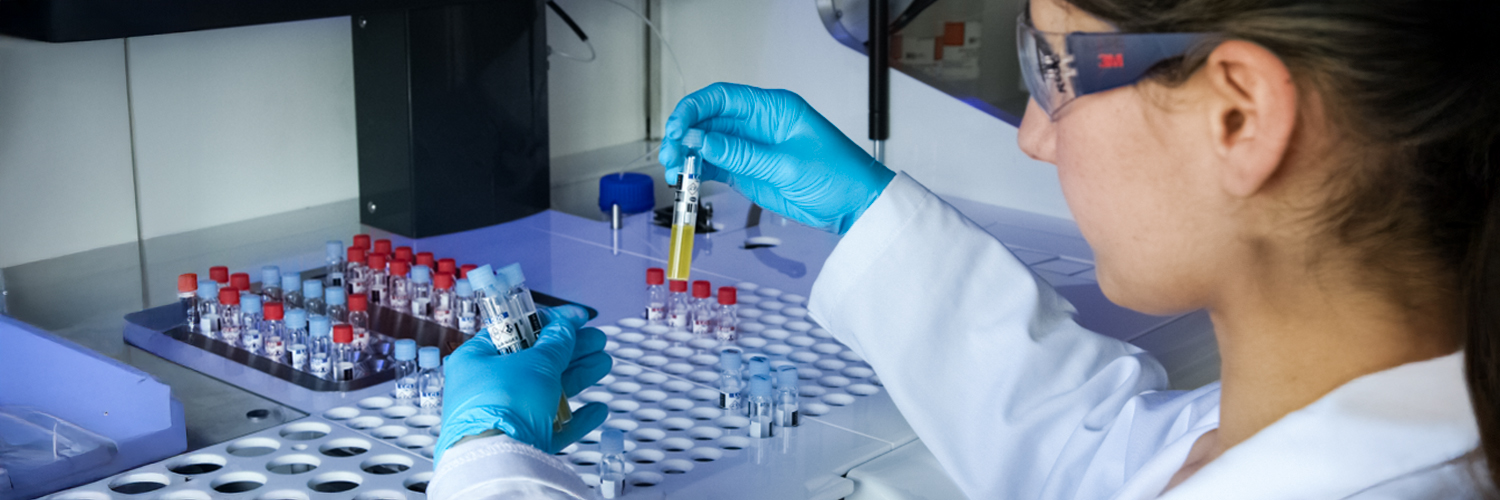 Opératrice de laboratoire manipulant des échantillons avec des gants bleus